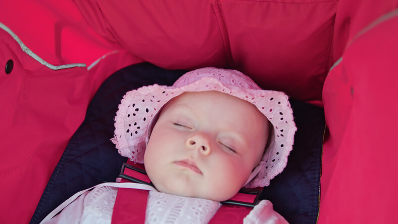 Baby der sover i barnevognen om sommeren