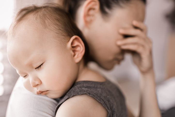Tired stressed mother holding baby
